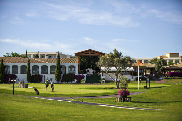 Golfers practice putting next to Dom Pedro Golf Clubhouse at Victoria golf course