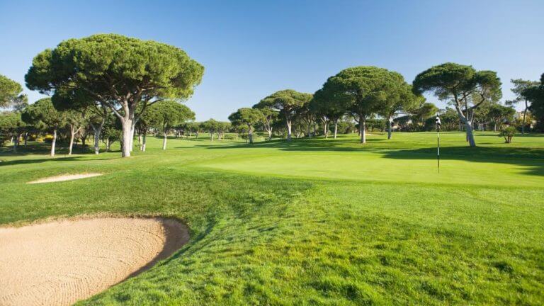 Lush green fairways contrast with bright blue sky at Dom Pedro's Old Course
