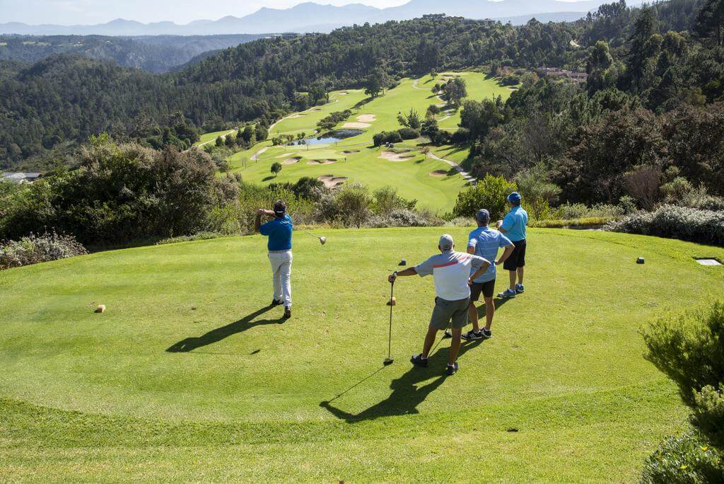Golfers tee off from an elevated tee